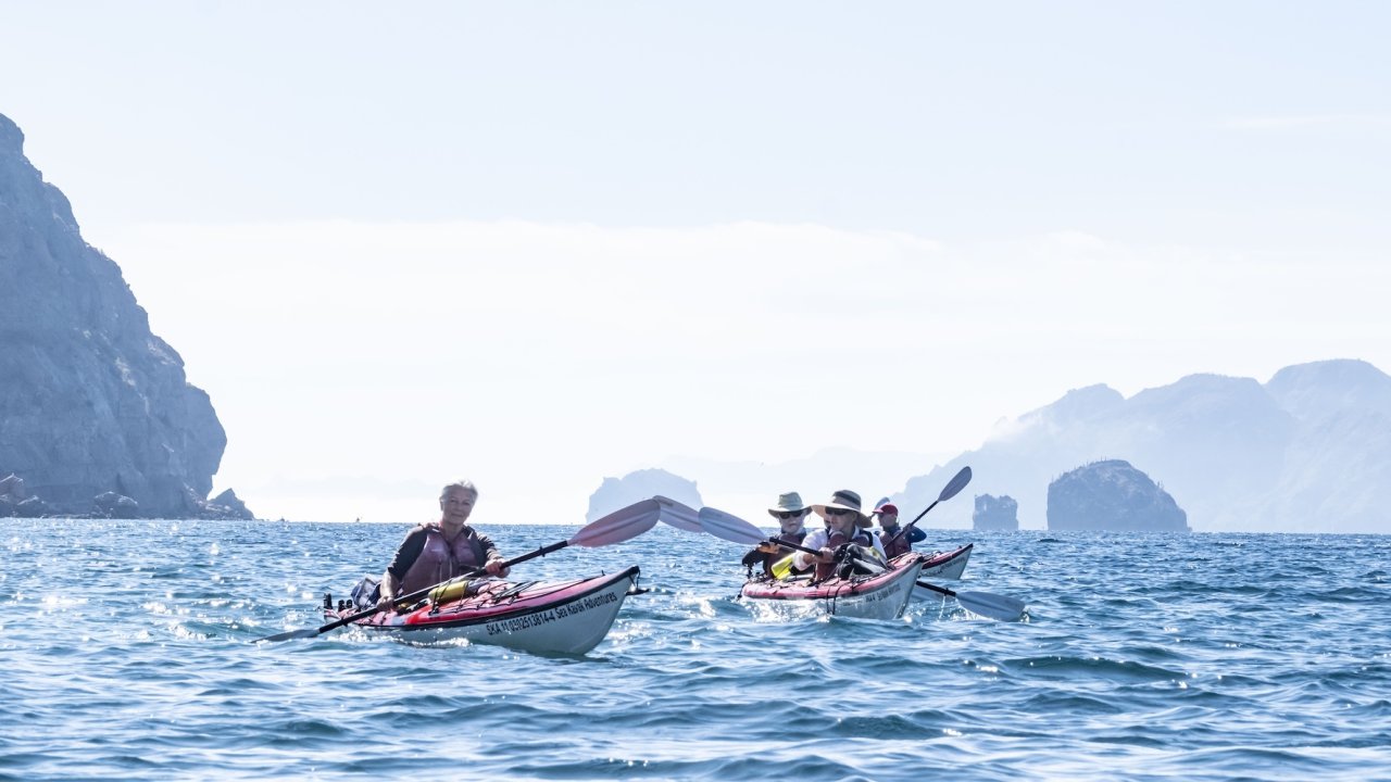 A group of sea kayakers paddling on a warm day in Baja.