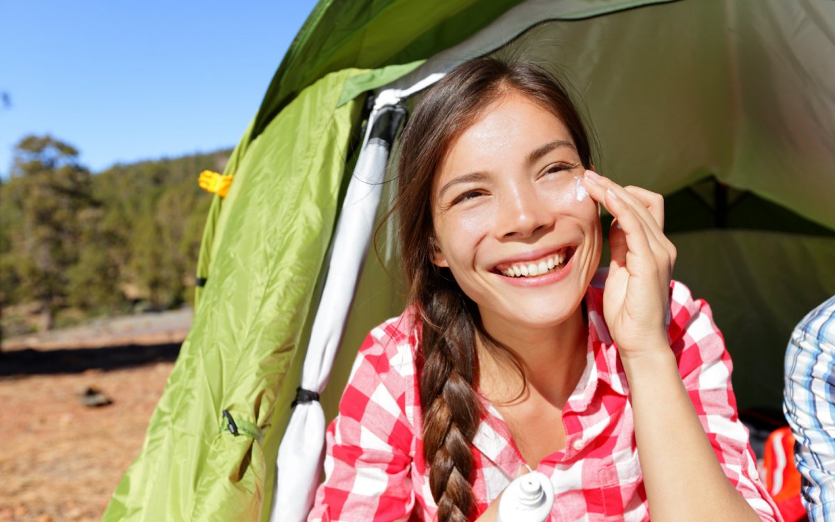 A woman putting on sunscreen while on a river rafting trip