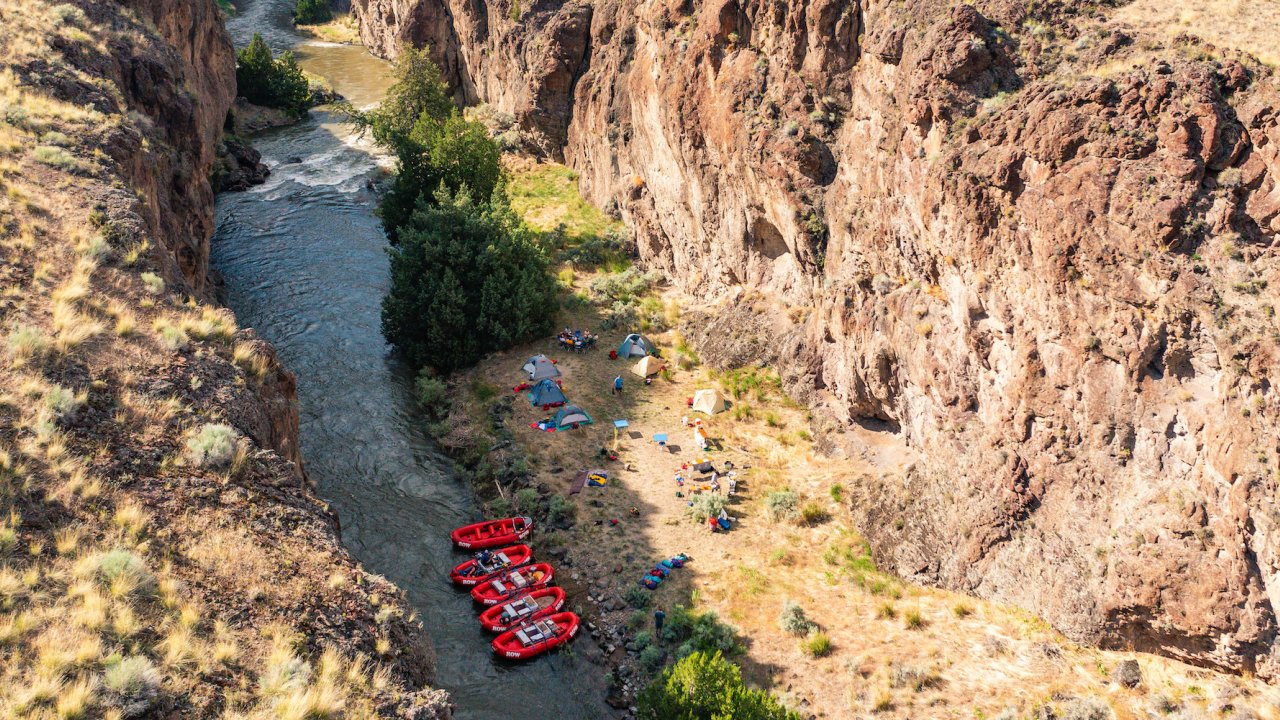 Birds eye view of a camping set up along the Bruneau River with red rafts in the water