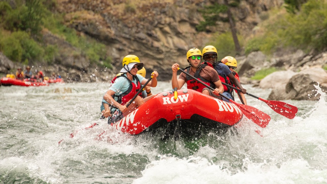 Group of travelers paddling through whitewater rapids on a guided rafting trip down the Middle Fork of the Salmon River in Idaho.