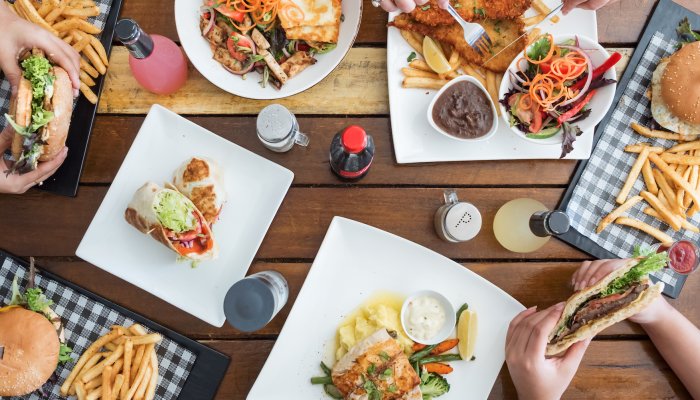 A lunch spread of sandwiches, burgers, and fries on a picnic table