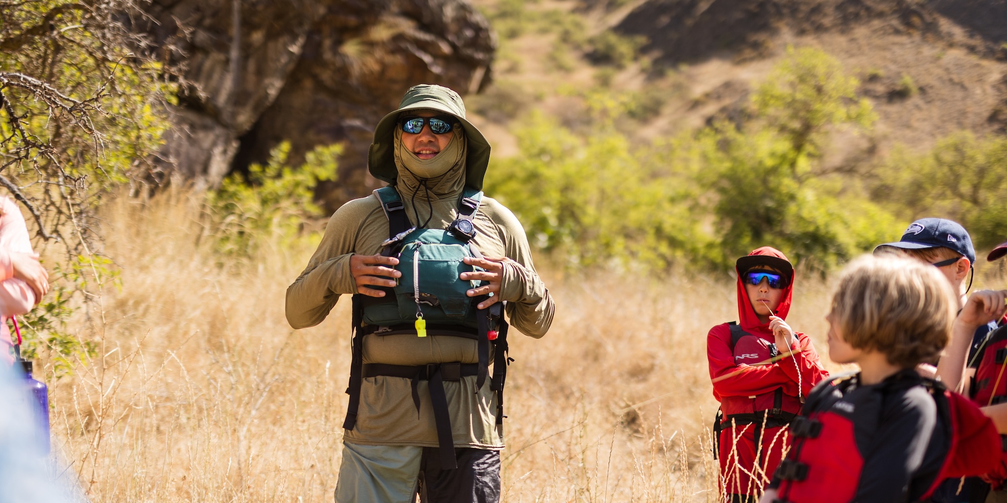A river guide wearing a buff while speaking to guests on a rafting trip. 