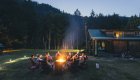 A group of whitewater rafters gathered around a campfire at Half Moon Bar Lodge in Oregon