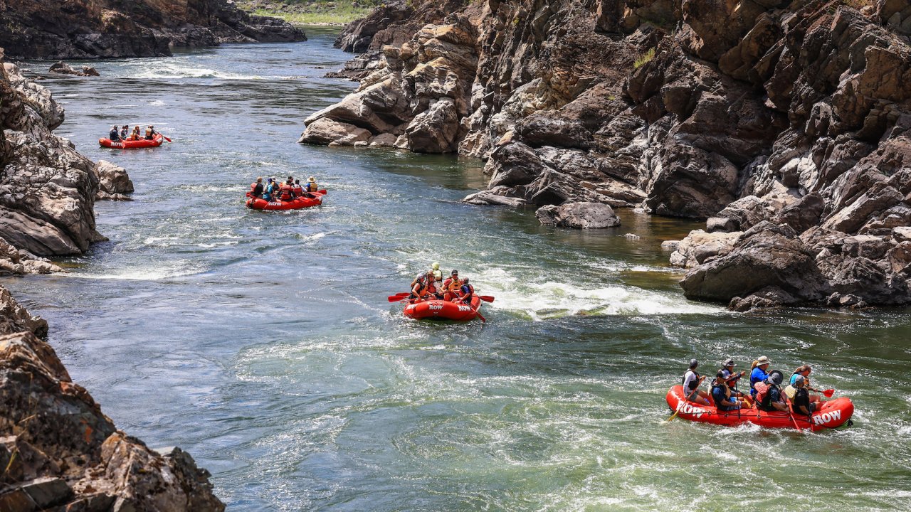 A lineup of red raft floating down the Clark Fork River in the Alberton Gorge in Montana