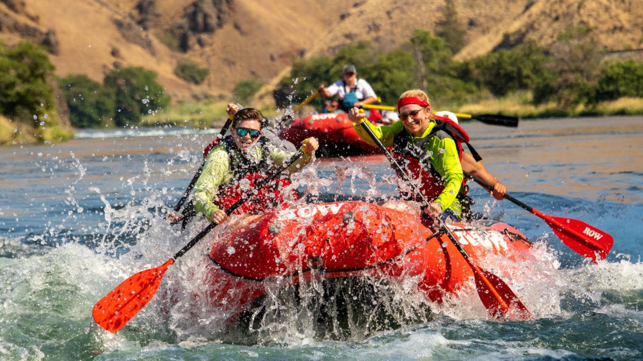 Rafting guests paddling a red whitewater raft on the Deschutes River