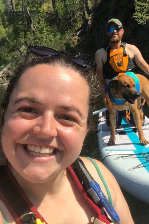 woman, man and dog floating on water with paddleboard