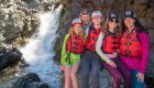 A family standing and smiling next to a waterfall in Oregon