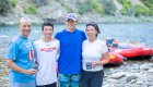 family smiling on a riverside beach while whitewater rafting in Idaho
