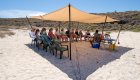 Group orientation under a tent on the beach before a day of kayaking