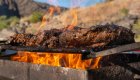 Steaks grilling over an open fire while on a Snake river rafting tour.