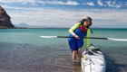 Happy sea kayaker getting out of their kayak on the beach in Baja, California