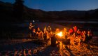 People sitting around a campfire under a clear starry nights sky in Idaho
