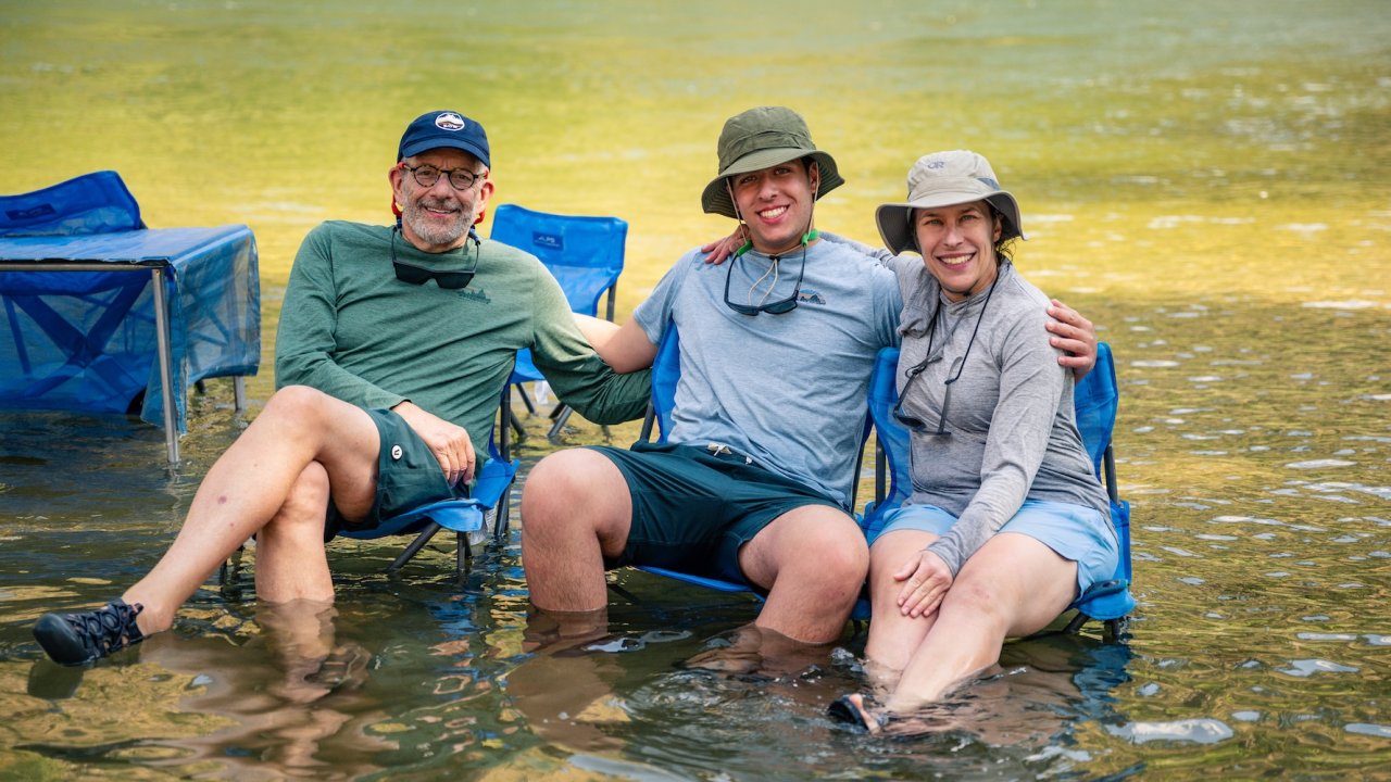 Family relaxing with chairs in the water during a main Salmon River rafting trip in Idaho.