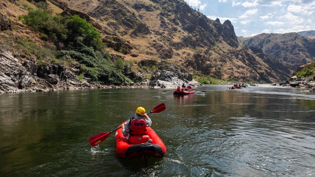 Rafting group paddling down the Snake River in Hells Canyon, Idaho, surrounded by dramatic canyon cliffs on a whitewater rafting tour.