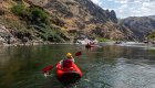 Rafting group paddling down the Snake River in Hells Canyon, Idaho, surrounded by dramatic canyon cliffs on a whitewater rafting tour.