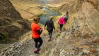 Group of hikers walking along a rocky trail above the Salmon River in Idaho, combining outdoor wellness travel with the excitement of rafting adventures.