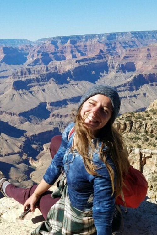female sitting on top of deep desert canyon