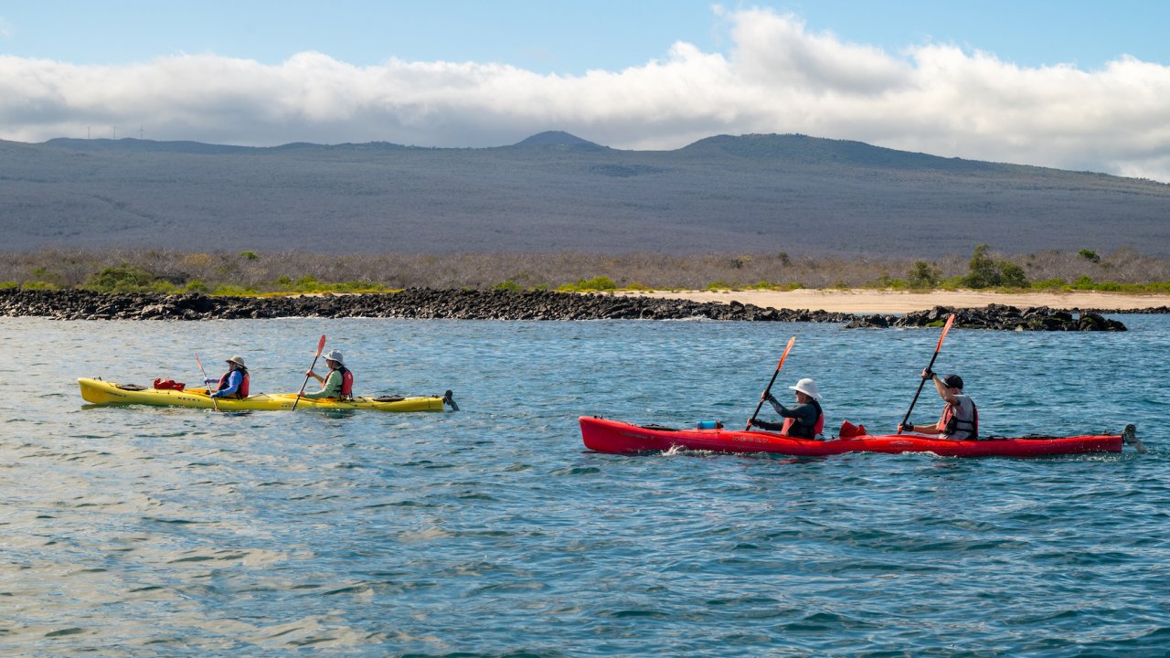 Tandem kayakers paddling off the beach in the Galapagos Islands
