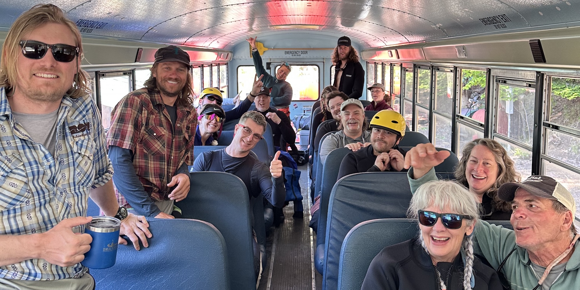 A group of people inside of a school bus dressed ready to float down a whitewater river.