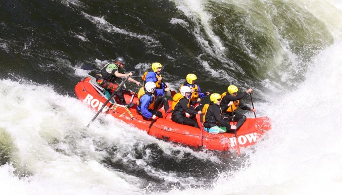 Six paddlers with yellow helmets in a red raft paddling through a big whitewater rapid on the Lochsa River in Idaho