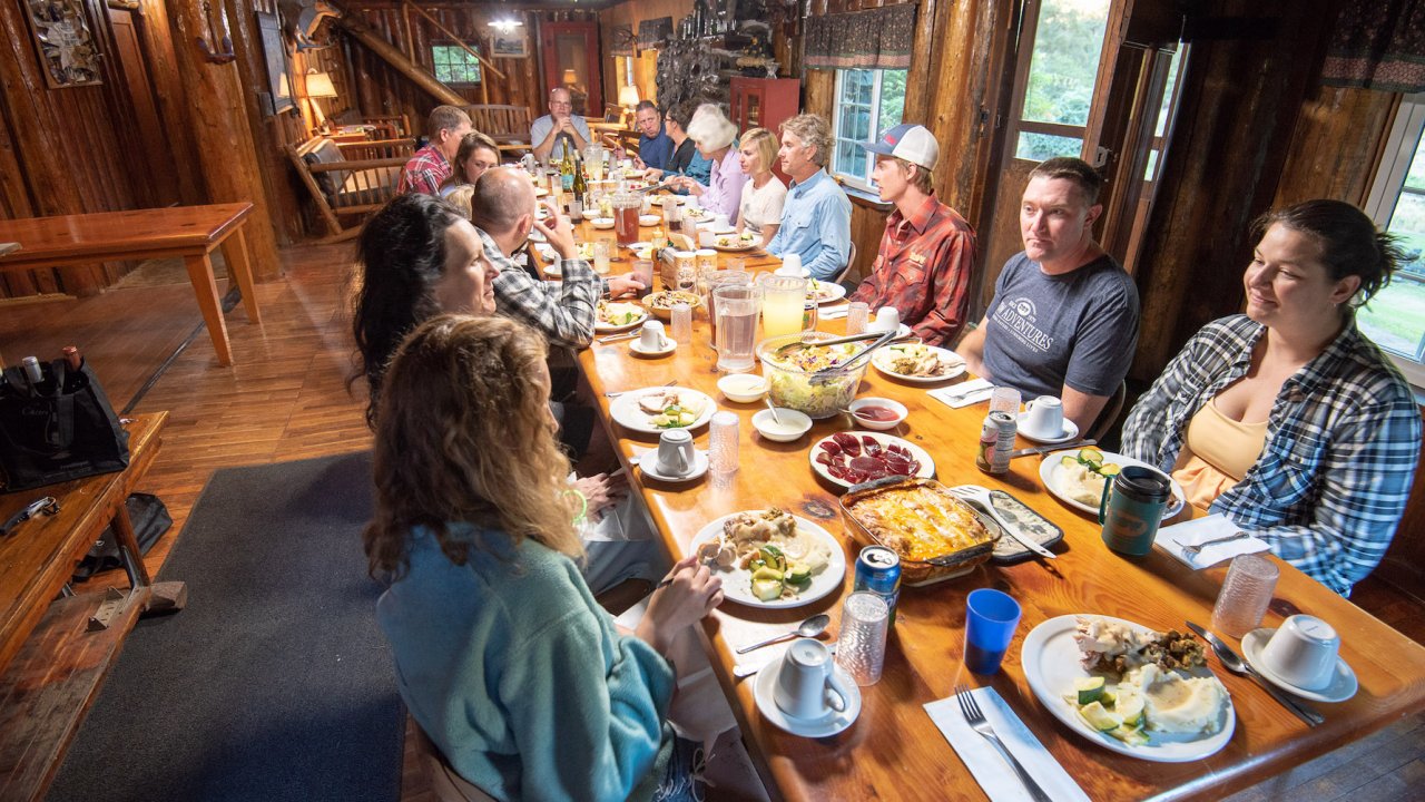 People sitting around a dining room table in a cabin in Oregon
