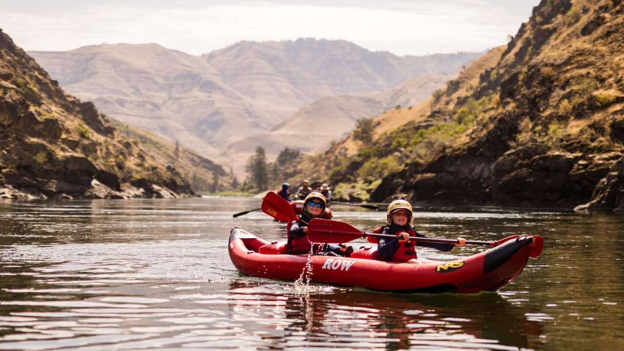 Rafters paddling inflatable kayaks on the Lower Salmon River, surrounded by dramatic Salmon River canyon walls in Idaho.