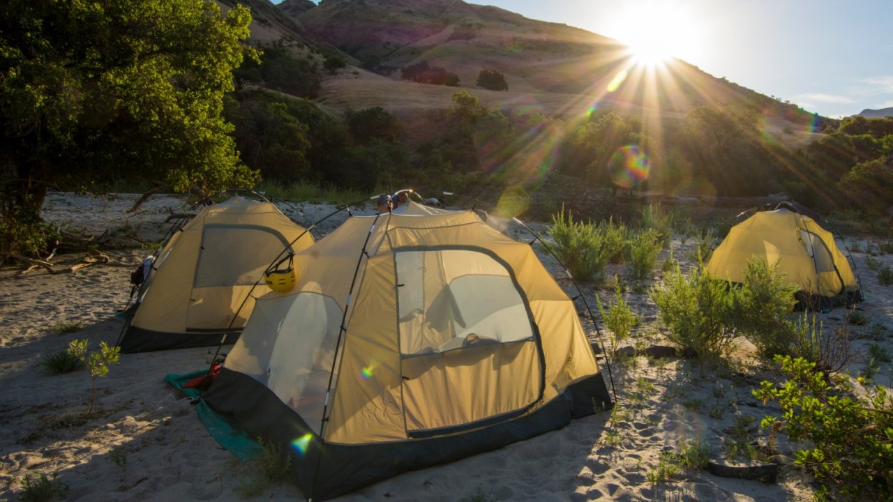 Tents on a sandy beach near the shores of the Salmon river during sunrise.