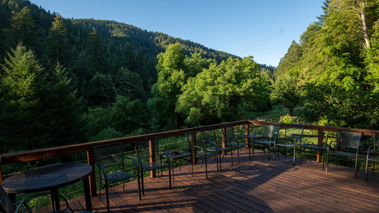 Deck with plastic chairs overlooking the forested Rogue River wilderness