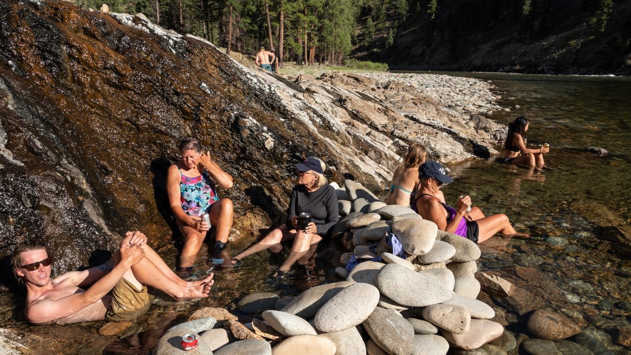 Guests soaking in natural hot springs along the Middle Fork Salmon River during a multi-day rafting and camping trip in Idaho.