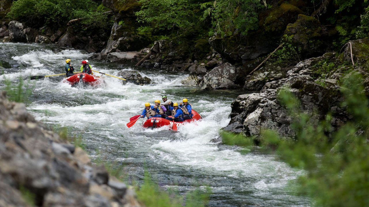 Upstream shot of two red rafts moving downstream through a narrow section of the St. Joe river in Northern Idaho