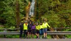 A group of bikers stop for a photo in front of a waterfall in Olympic National Park
