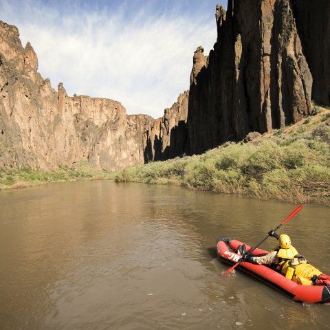 Person in a red inflatable kayak paddling down the Owyhee River in Idaho