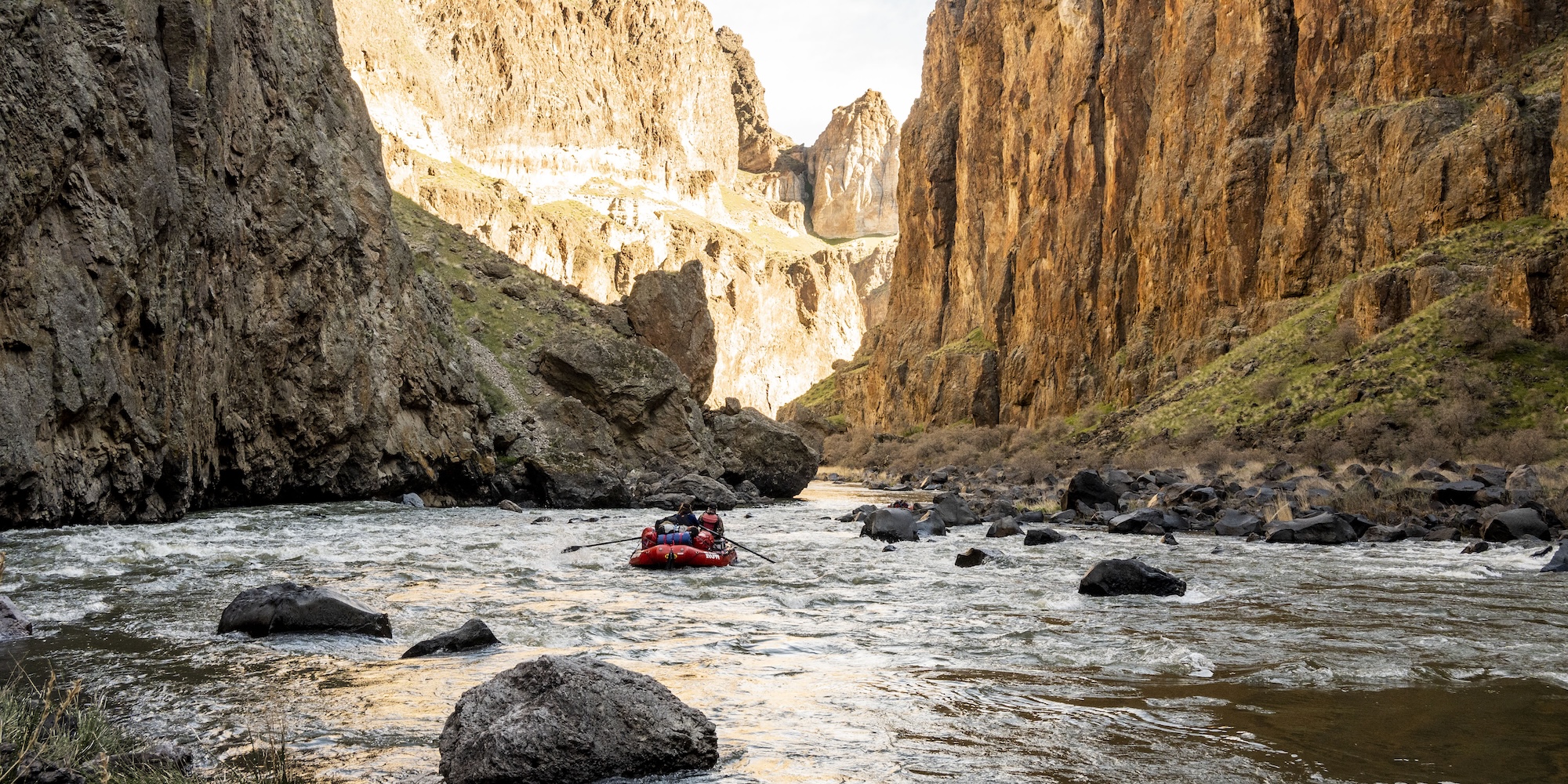 A red ROW Adventures raft floating down a rocky section of the Owyhee river in Oregon.