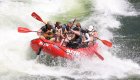 A red ROW Adventures raft going through a splashy rapid on the Clark Fork river in Montana.