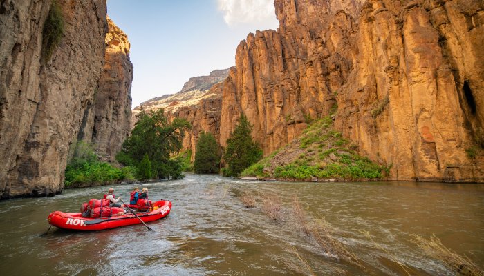 Three people on a red raft floating the Bruneau River