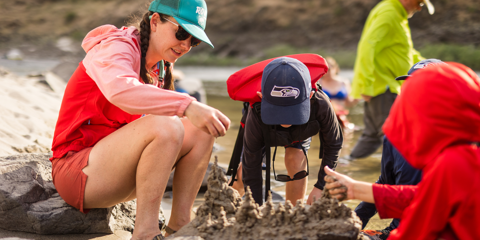 A river jester guide building a sand castle with a young boy on a family rafting trip in Idaho