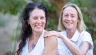 Two women smiling during a riverside wellness retreat in Idaho, where relaxation and connection are part of the whitewater rafting experience.