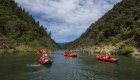 Rafts and inflatable kayaks floating on the Rogue River in Oregon, combining rafting excitement with overnight camping along the riverbanks.