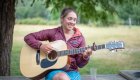 girl sitting on table playing guitar