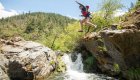 Girl jumping off a rock into a small pool below a waterfall in Oregon