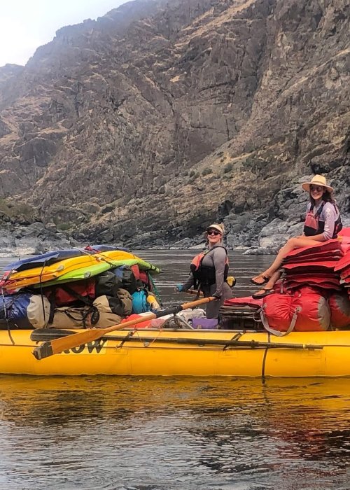 Two river guides floating downstream on a yellow ROW raft.