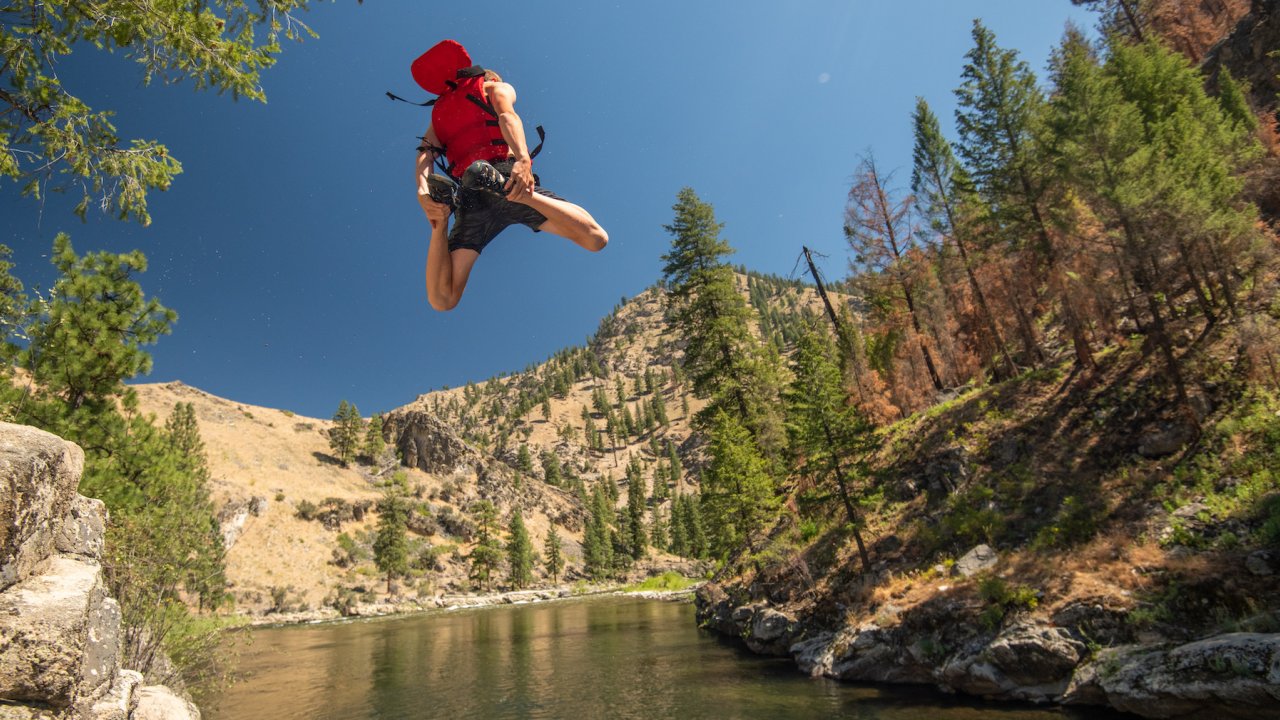 A person cliff jumping into the Middle Fork Salmon River on a sunny summer day