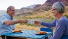 A couple sitting at a camp table enjoying a meal and tea after a day of hiking in Hells Canyon, Idaho.