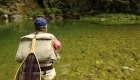 Person casting a yellow line into the St. Joe River in North Idaho with a net behind his back