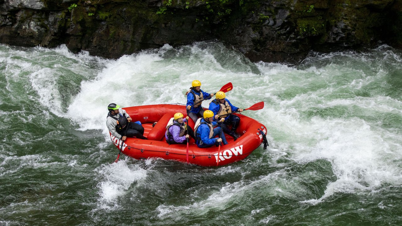 Birds eye view of a red raft with a guide and passengers rafting through the St. Joe river