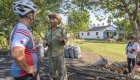Biker with a helmet talking to a Cuban local on the street in front of a home
