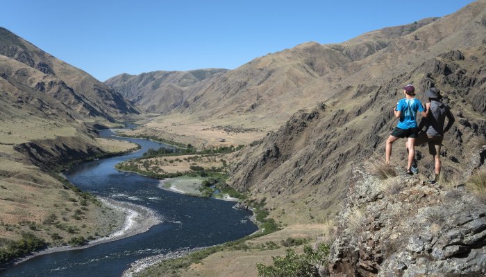 A couple standing above the Hells Canyon National Recreation Area overlooking the Snake River on a hike