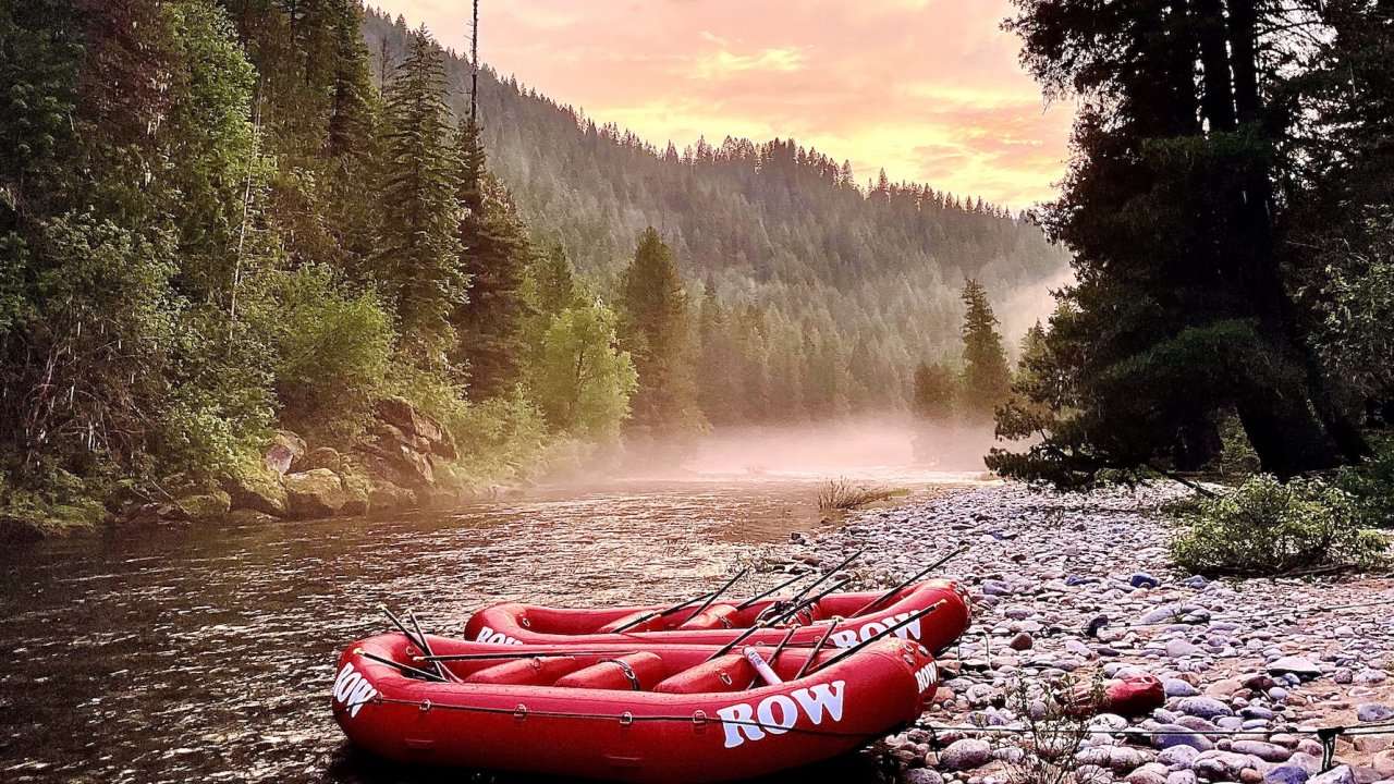 Two red ROW branded boats tied off to the shore at sunset