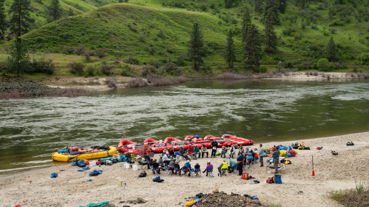 people sitting in a circle near a river