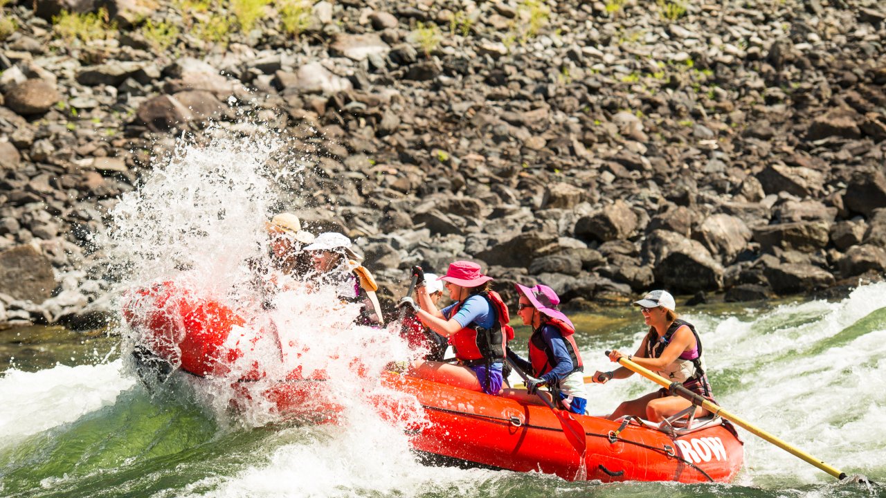 Group of guests on a raft getting splashed in the middle of a rapid